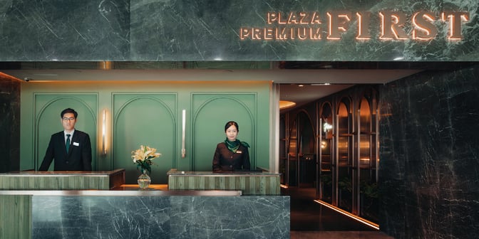 The entrance to Plaza Premium First at Macau International Airport features a reception desk staffed by attendants ready to assist guests.