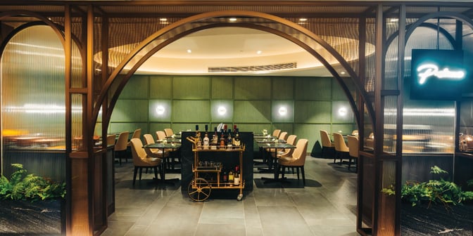 The dining area at Plaza Premium First, Macau International Airport, features table seating and a central beverage cart.