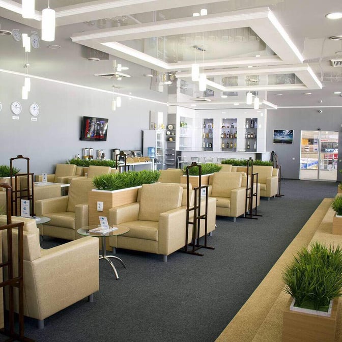 The business lounge at Manas International Airport features comfortable seating, a self-serve beverage area, and a bar with various drinks.