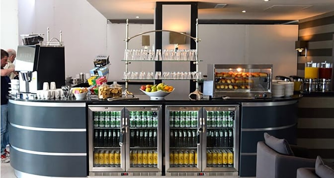 The Aspire Lounge at Manchester Airport features a beverage station with a variety of drinks, snacks, and glassware.