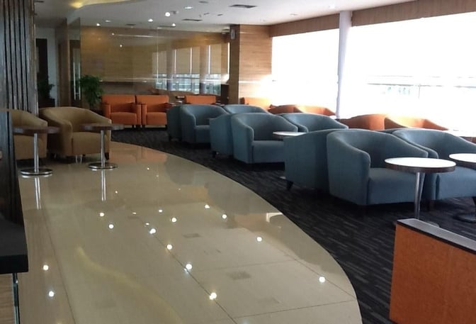 The seating area in Saphire Lounge at Kualanamu International Airport features comfortable armchairs and small tables for passenger relaxation.
