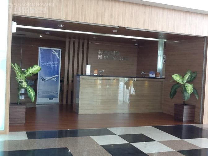 The entrance to the Saphire Lounge at Kualanamu International Airport features a reception desk with decorative plants and informational signage.