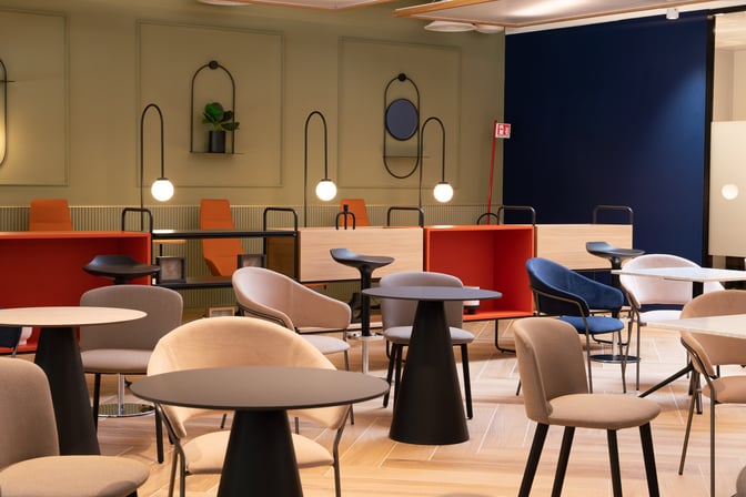 The HelloSky lounge at Milan Bergamo Airport features a seating area with round tables and a variety of chairs for travelers.