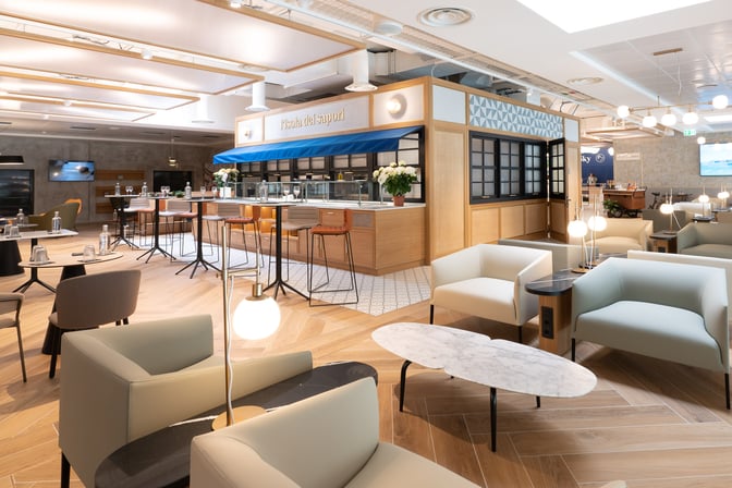 The HelloSky Lounge at Milan Bergamo Airport features a bar area with high stools and a seating area with tables and chairs.