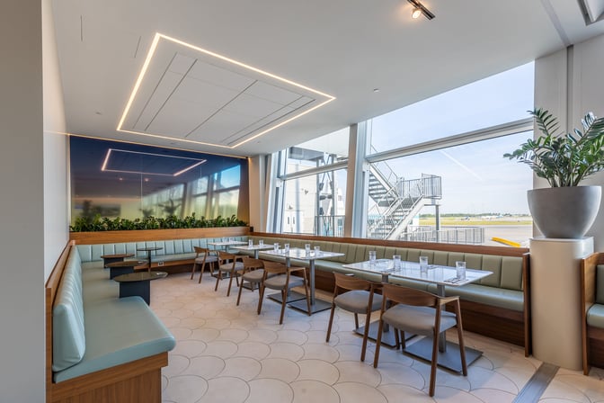 The Aspire International Lounge at Montreal-Trudeau Airport features booth and table seating with views of the airport tarmac.