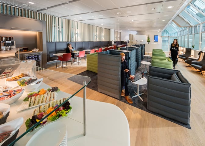 The Munich Airport Lounge features semi-private seating areas and a self-serve food station with sandwiches and snacks.