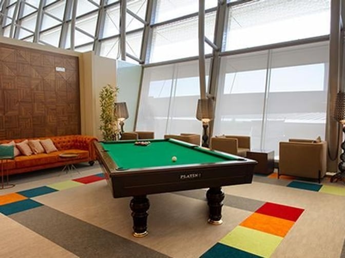 The Primeclass Lounge at Muscat International Airport features a billiards table and seating area with armchairs and a sofa.