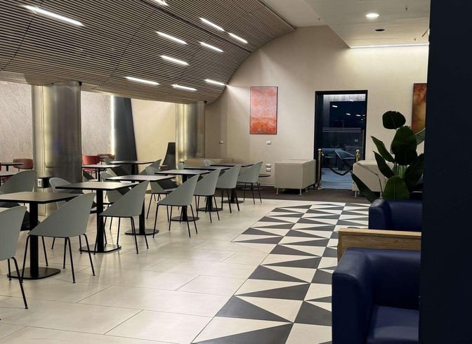 The seating area in Pearl Lounge at Naples International Airport features tables with chairs and couches, providing a comfortable space for travelers.