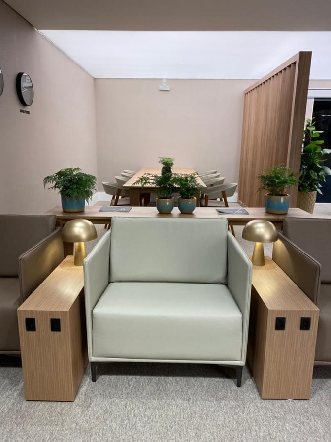 The seating area in W Lounge Navegantes features armchairs with side tables and a communal table in the background.