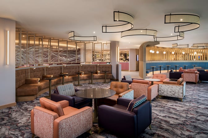 The Suite by Aspire at Newcastle Airport features diverse seating options, including booth and lounge chairs, with a view of the bar area.