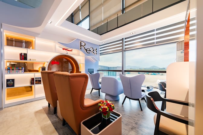 The ASG Sky Lounge at Noi Bai International Airport features comfortable seating with airport views and a reading area with bookshelves.