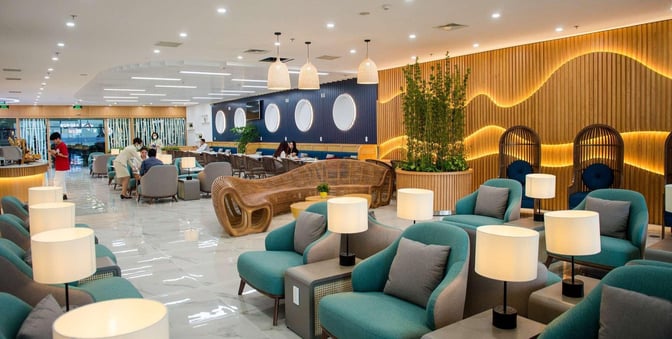 The First Lounge by Bamboo Airways at Noi Bai International Airport features comfortable seating areas with tables and ambient lighting.