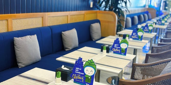 Booth seating in the First Lounge by Bamboo Airways at Noi Bai International Airport features tables with festive decorations and cushioned benches.