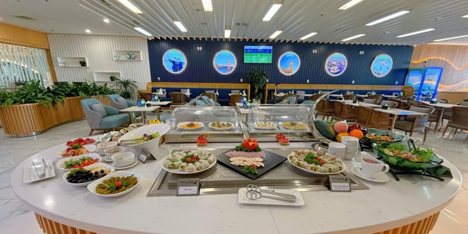 The First Lounge by Bamboo Airways at Noi Bai International Airport features a self-serve food station with a variety of dishes and seating areas.