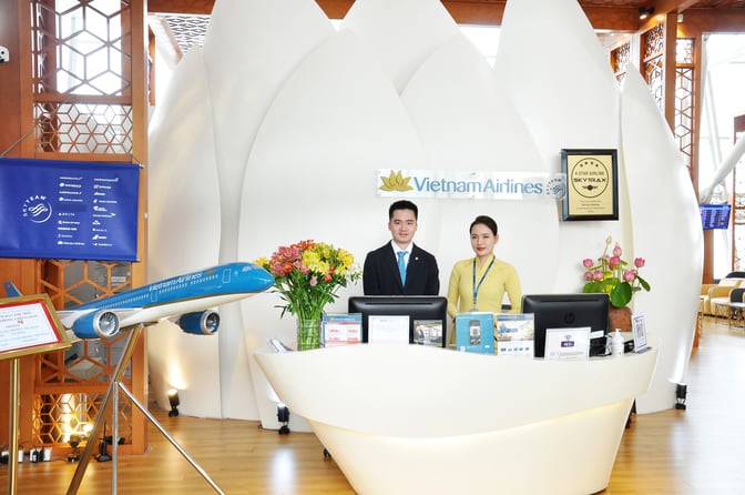 The Vietnam Airlines Lotus Lounge reception at Noi Bai International Airport features staff assistance, informational displays, and a model aircraft.