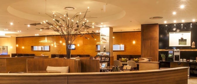 The Aspire Lounge at O. R. Tambo International Airport features booth seating and a coffee station with self-serve options.
