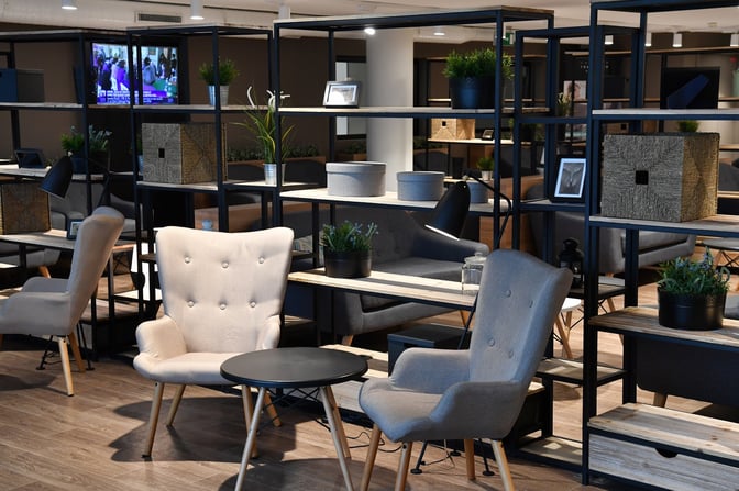 The seating area in the Premium Traveller Lounge at Paris-Orly Airport features comfortable chairs and tables with decorative shelving.