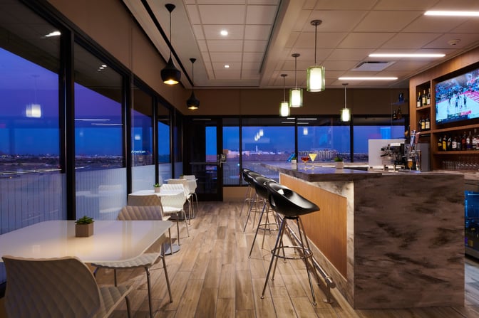 The Escape Lounge at Phoenix Sky Harbor features a bar with counter seating and tables, offering views of the airport.