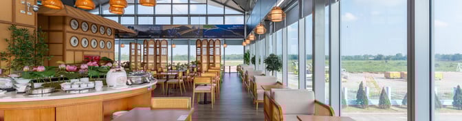 The SH Premium Lounge at Phu Cat Airport features a dining area with table seating and views of the airport tarmac.