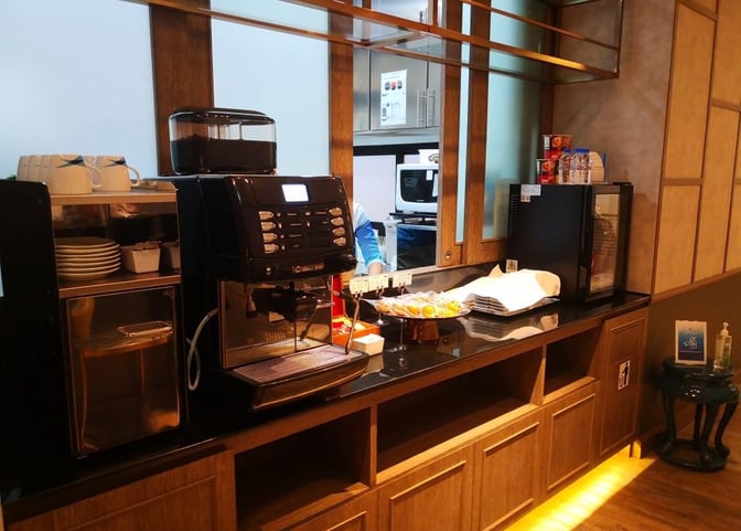 The Bangkok Airways Blue Ribbon Lounge at Phuket International Airport features a self-serve coffee station with a variety of beverages and snacks.