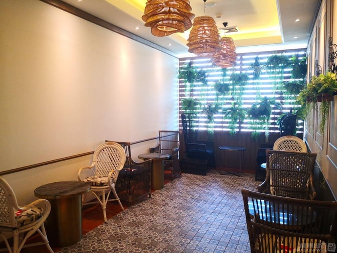 The seating area in Bangkok Airways Blue Ribbon Lounge at Phuket International Airport features wicker chairs and tables with a plant-adorned wall.