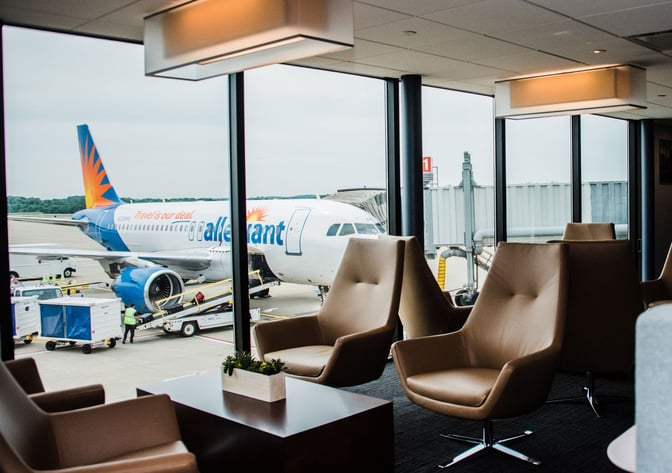 Comfortable seating in The Club PIT lounge at Pittsburgh International Airport offers views of the tarmac and parked aircraft.