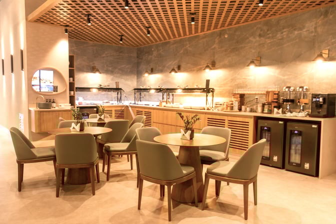 The W Premium Lounge in Porto Alegre features a dining area with round tables and a self-serve buffet station.
