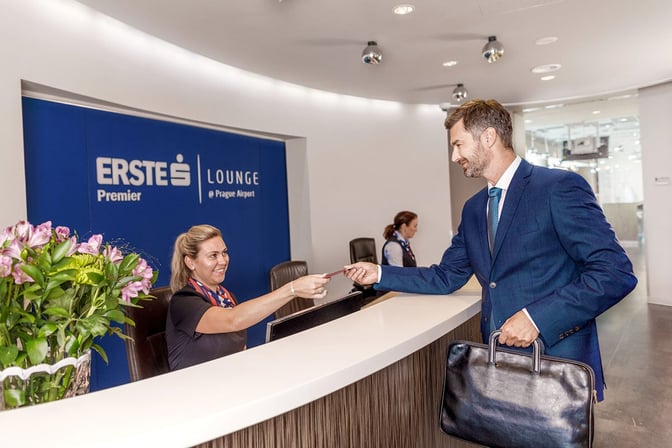 The reception area of the Erste Premier Lounge at Prague Airport features a check-in counter where staff assist arriving guests.