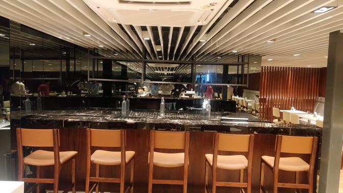 The Earth Lounge at Pune Airport features a bar area with counter seating and a view of the dining space.