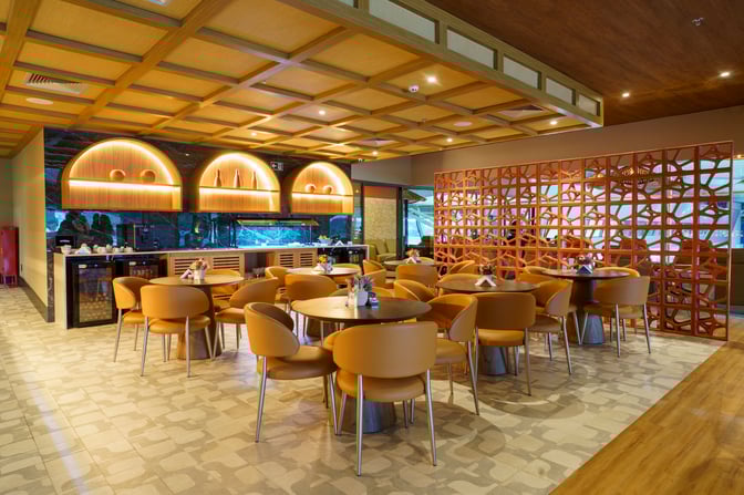 The W Lounge Recife Frevo features a seating area with round tables and chairs, adjacent to a self-serve beverage station.