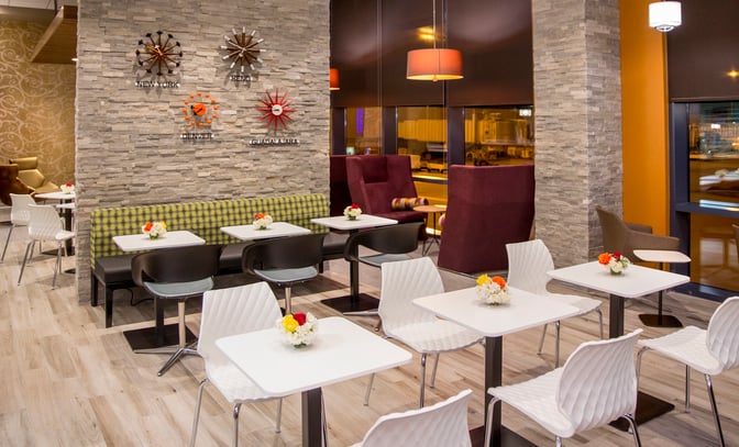 The seating area in the Escape Lounge at Reno–Tahoe International Airport features tables with chairs and booth seating for dining.