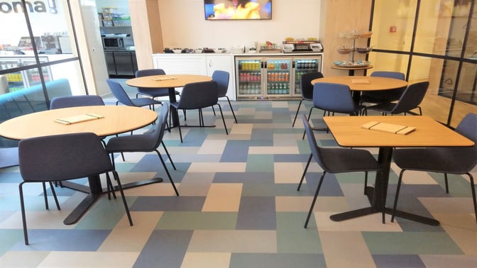 The HelloSky lounge at Leonardo da Vinci-Fiumicino Airport features a seating area with tables, chairs, and a self-serve beverage station.