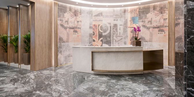 The reception area of the Plaza Premium Lounge at Leonardo da Vinci-Fiumicino Airport features a curved desk and decorative wall art.
