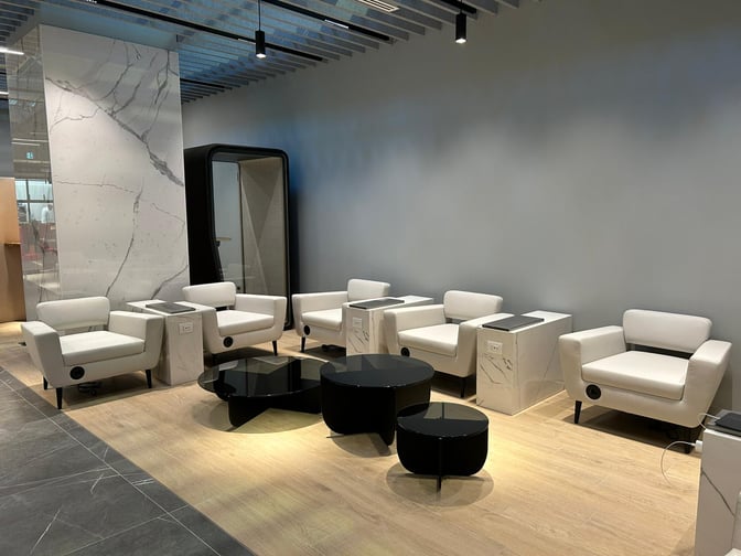 Seating area in Primeclass Lounge at Leonardo da Vinci-Fiumicino Airport features comfortable chairs with charging stations and small tables for travelers.