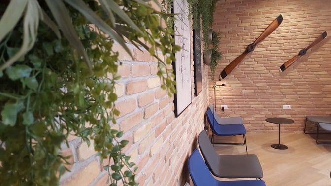Seating area in Prima Vista Lounge Domus at Leonardo da Vinci-Fiumicino Airport features chairs, small tables, and aviation-themed decor.