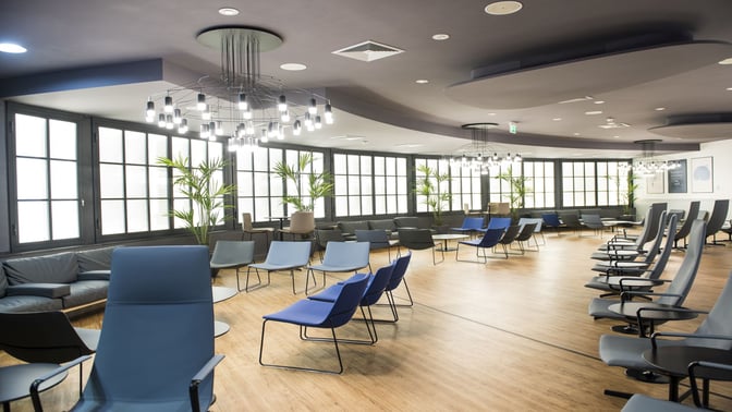 The Prima Vista Lounge at Leonardo da Vinci-Fiumicino Airport features spacious seating with chairs and tables, providing a comfortable waiting area.