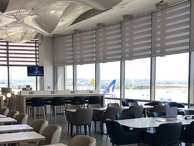 The seating area in Plaza Premium Lounge at Sabiha Gokcen Airport offers tables and chairs with views of the runway.
