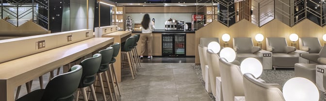 The Plaza Premium Lounge at Sabiha Gokcen International Airport features a seating area with armchairs and a self-serve beverage station.