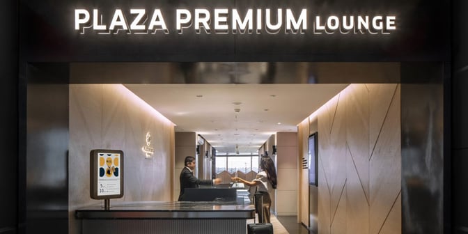 The entrance to the Plaza Premium Lounge at Sabiha Gokcen Airport features a reception desk and signage for guest assistance.