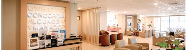 The Concordia Lounge at Sam Ratulangi International Airport features a seating area with armchairs and a reception desk displaying promotional materials.