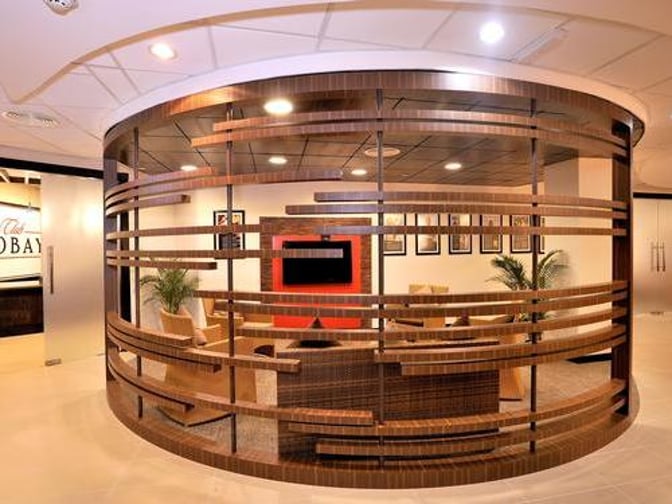 The Club Mobay Arrivals Lounge at Sangster International Airport features a seating area with a television and framed artwork.