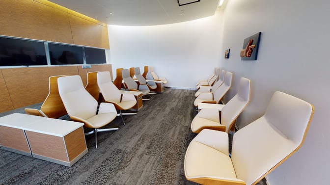 The seating area in The Club SEA at Seattle-Tacoma International Airport features rows of ergonomic chairs with nearby charging outlets.