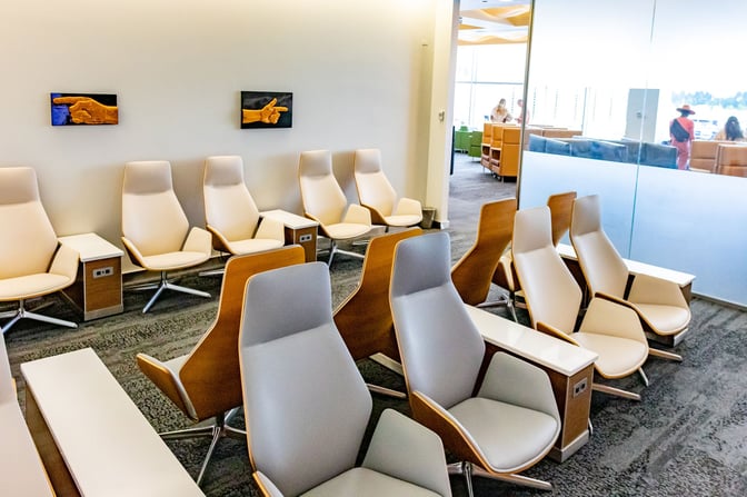 The seating area at The Club SEA in Seattle-Tacoma International Airport features ergonomic chairs with individual side tables and power outlets.