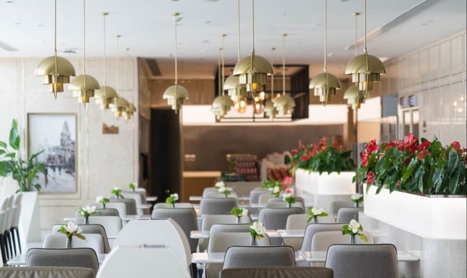 Seating area in No. 170 VIP Lounge at Shanghai Pudong Airport features tables with individual chairs and decorative plants.