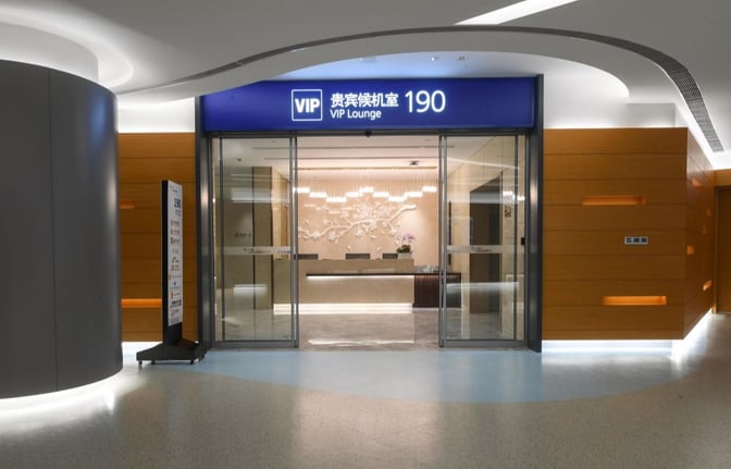 The entrance to No. 190 VIP Lounge at Shanghai Pudong International Airport features sliding glass doors and a reception desk inside.