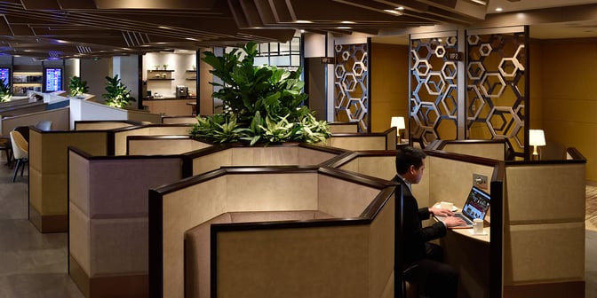 Semi-private workstations in Plaza Premium Lounge at Singapore Changi Airport offer individual seating with laptop space and nearby greenery.