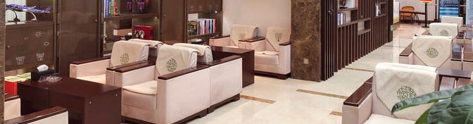 The seating area in the V3 China Eastern Lounge at Sunan Shuofang International Airport features armchairs and bookshelves for passenger relaxation.