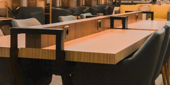 The Concordia Lounge at Syamsudin Noor Airport features a seating area with tables equipped with power outlets for travelers.