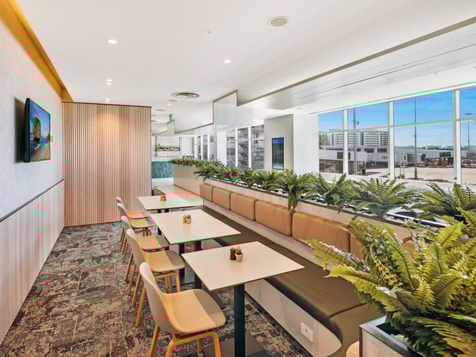 Booth seating at Plaza Premium Lounge in Sydney Airport offers semi-private dining with views of the tarmac and runway.