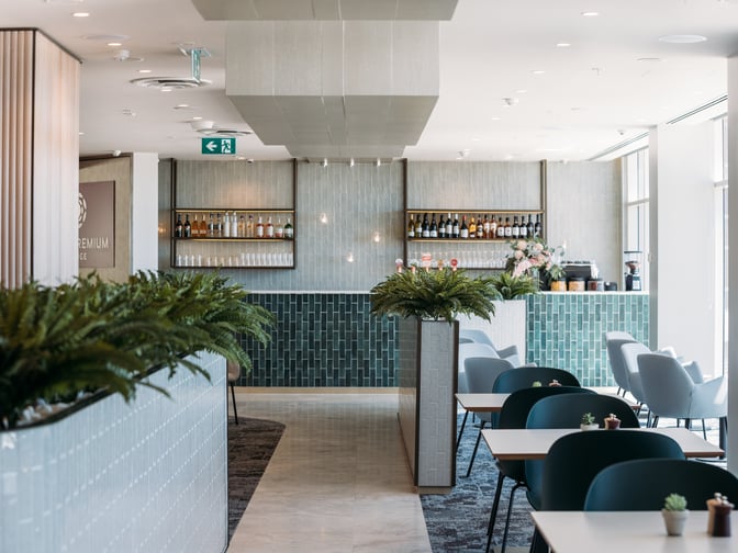 The Plaza Premium Lounge at Sydney Airport features a bar area with a selection of beverages and adjacent seating for guests.